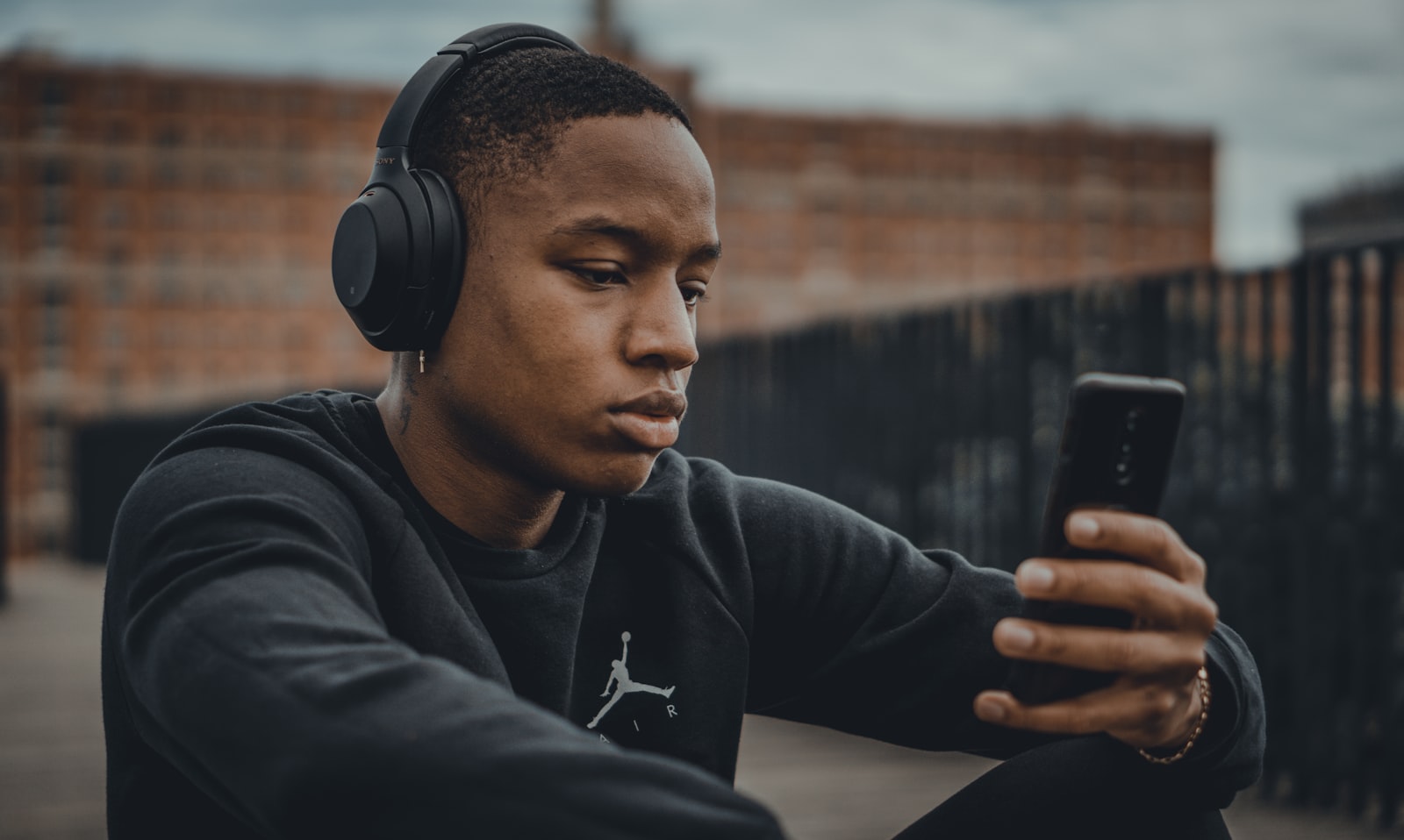 Pessoa sentada ouvindo música pelo celular usando fones de ouvido