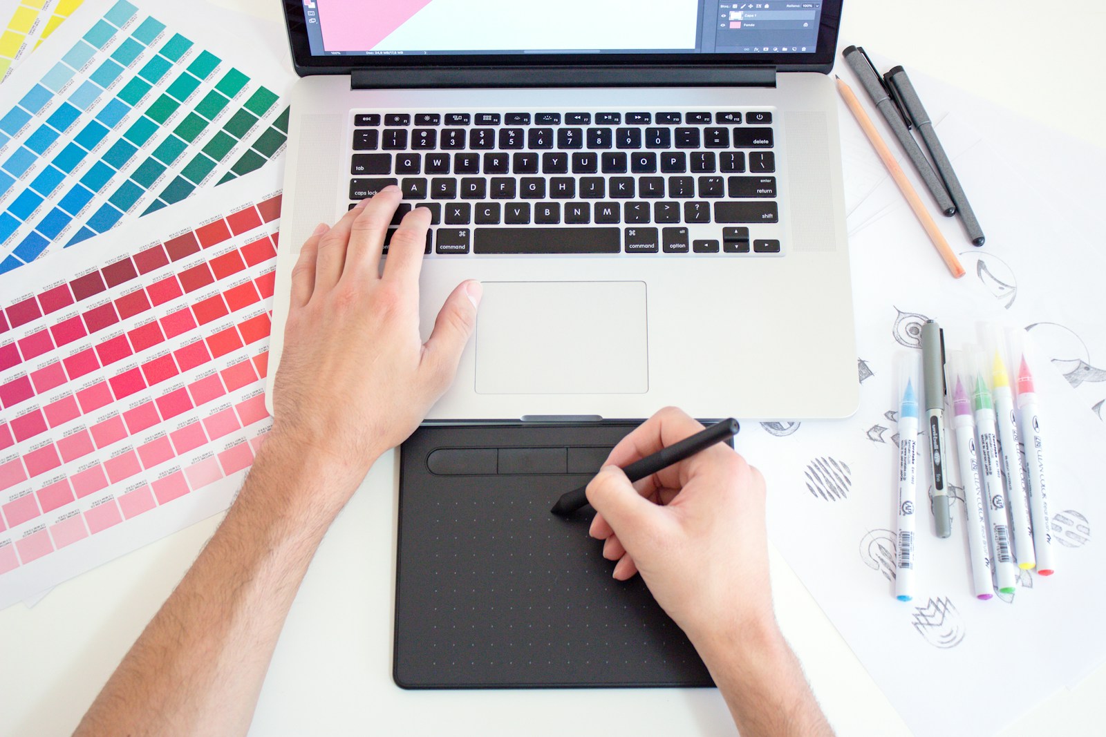 Designer trabalhando em laptop com paleta de cores, ilustrando o uso de ferramentas de design com IA como o Canva Magic Studio