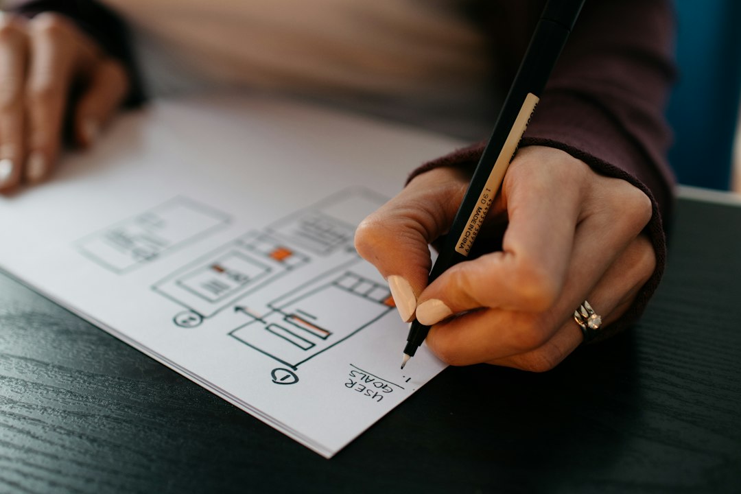Pessoa desenhando o rascunho das telas de um aplicativo no papel, ideia que o Lovable transforma em app funcionando
